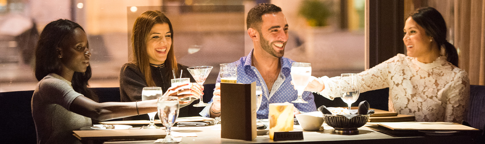 Four guests enjoying drinks and raising their glasses in Cheers!