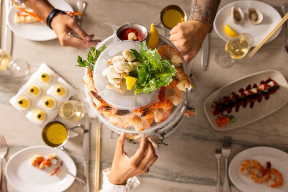 Hands reaching for pieces of chilled seafood on ice display